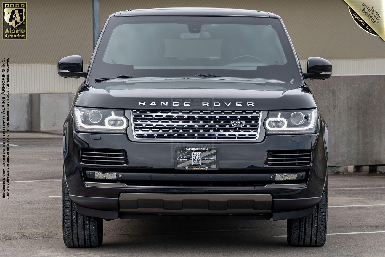 Front view of a black Range Rover SUV parked in an outdoor lot, showcasing its grille and headlights. Brand logos and dealership plates are visible on the vehicle.