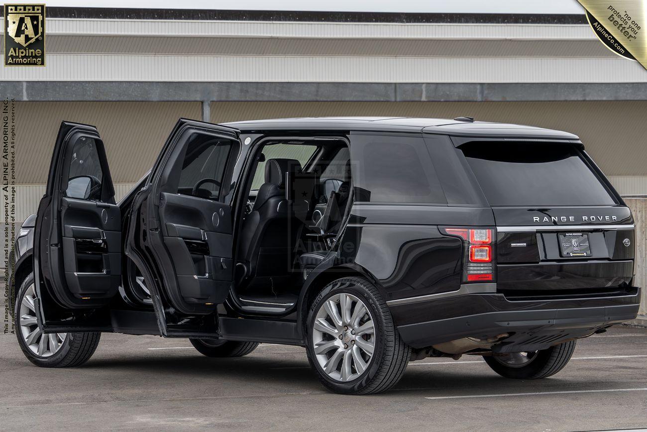 A black Range Rover Autobiography SUV with its rear and passenger side doors open, parked in front of a modern building.