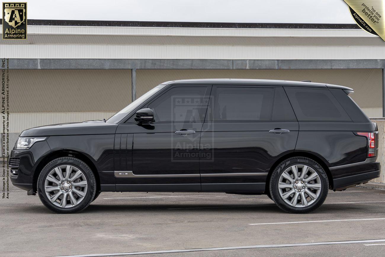 A driver side view of a black Range Rover Autobiography SUV with tinted windows, parked on an outdoor lot, displaying branding for Alpine Armoring.