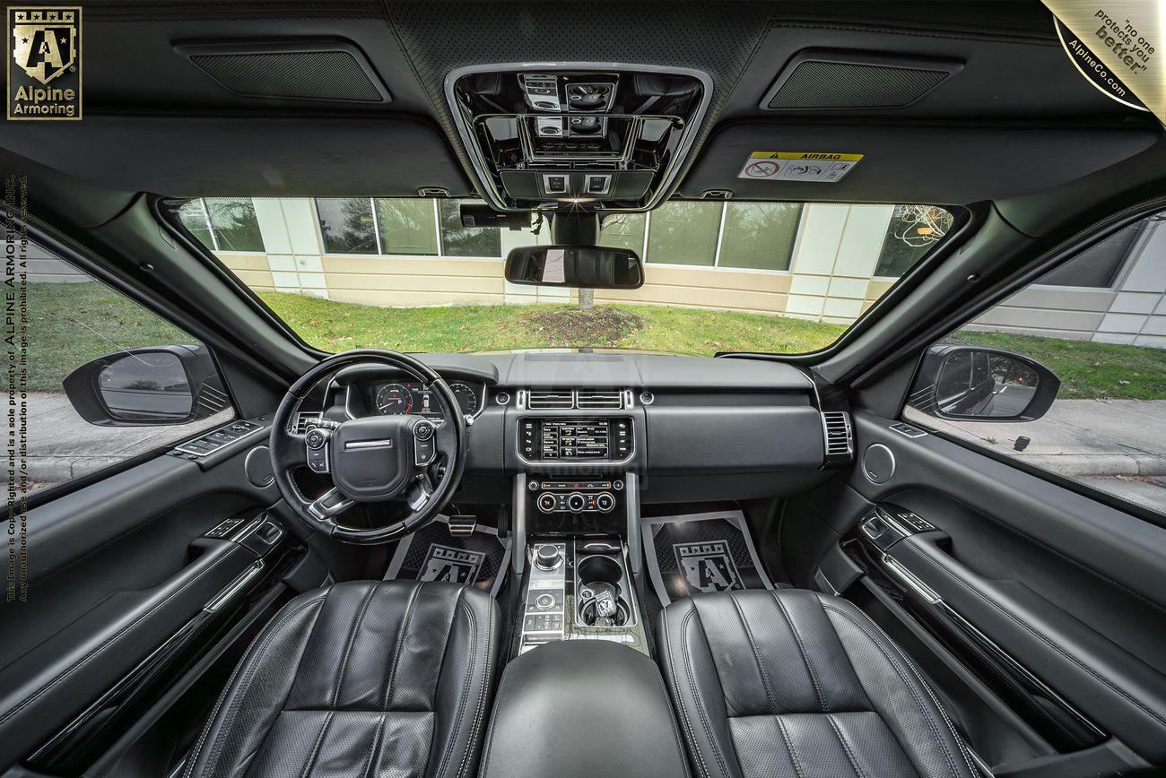 Interior of an armored  Range Rover Autobiography featuring black leather seats, a steering wheel, a central display screen, and various control buttons on the dashboard and center console.