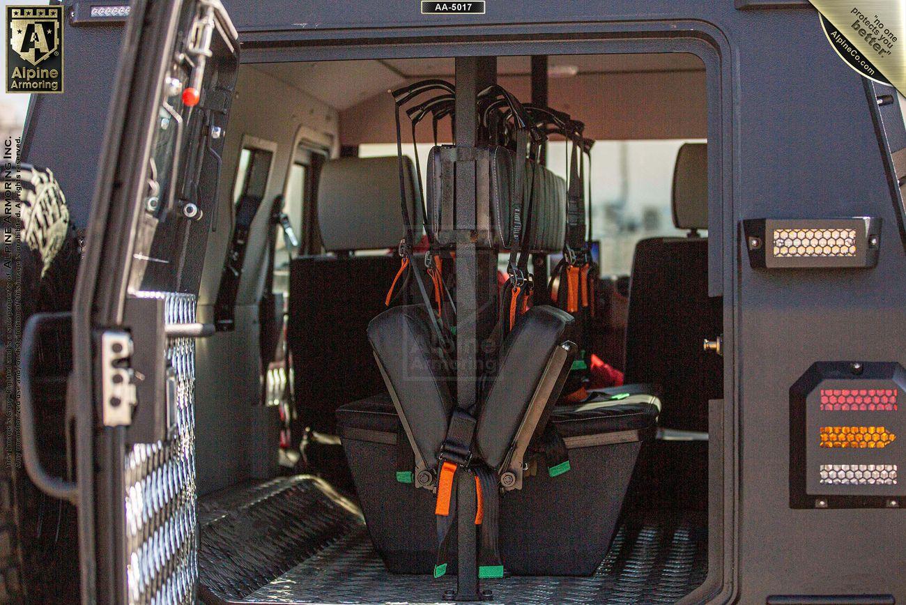 Interior of a CUDA vehicle with a seating arrangement that includes mounted metal frames and safety straps, designed for carrying equipment or personnel.