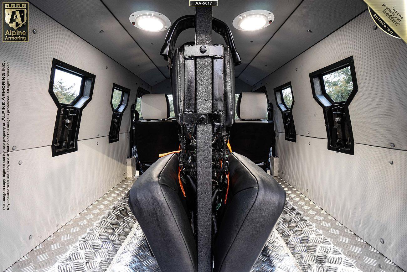 Interior of a SWAT APC CUDA with two bench seats, sturdy metal walls and floor, and a central supporting structure.