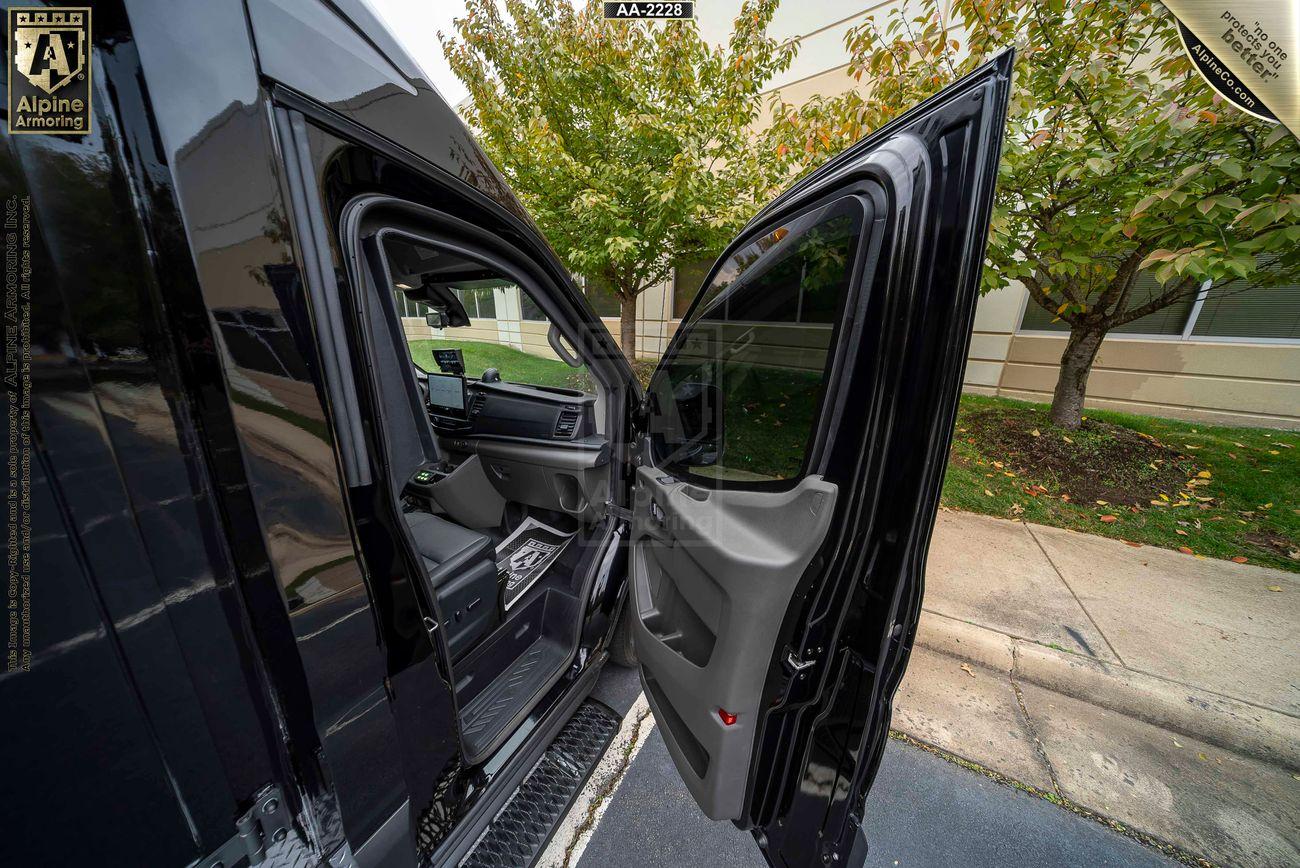 The image shows the open sliding door of a Pointer van, revealing the interior. The van is parked on a street with trees and a building in the background.