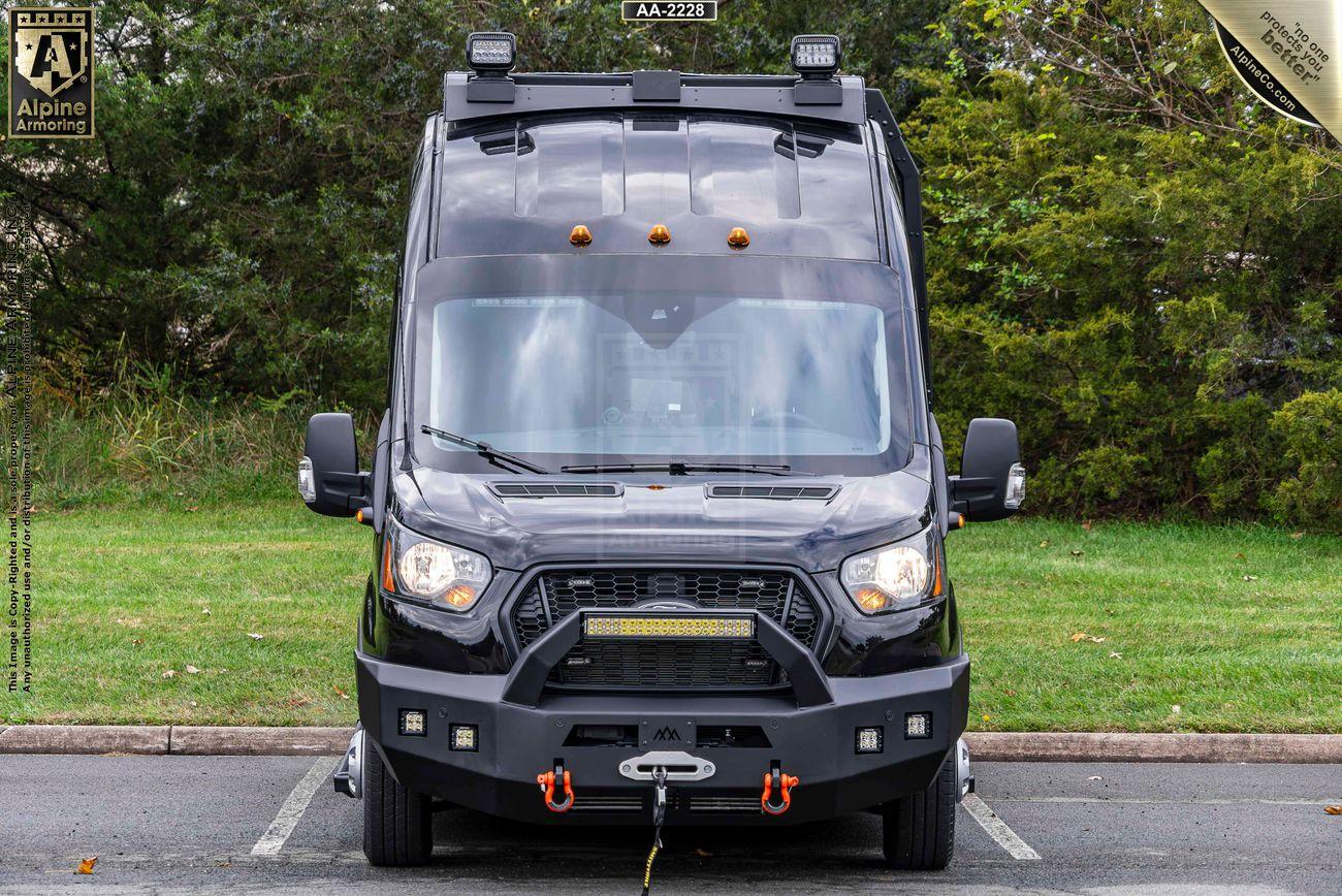 Front view of a black off-road equipped Pointer Van with a winch and other attachments, parked in an outdoor setting with trees in the background.