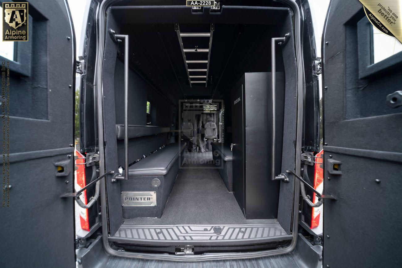 Interior view of a black armored Pointer Van, showing seating and storage arrangements with reinforced panels and safety features.