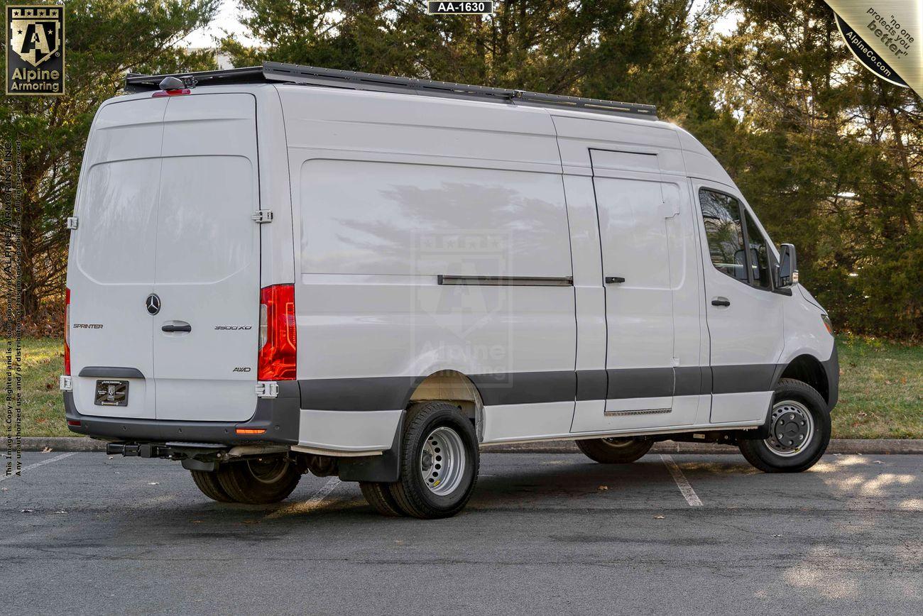 A white Sprinter van is parked outdoors on a paved surface with trees in the background.