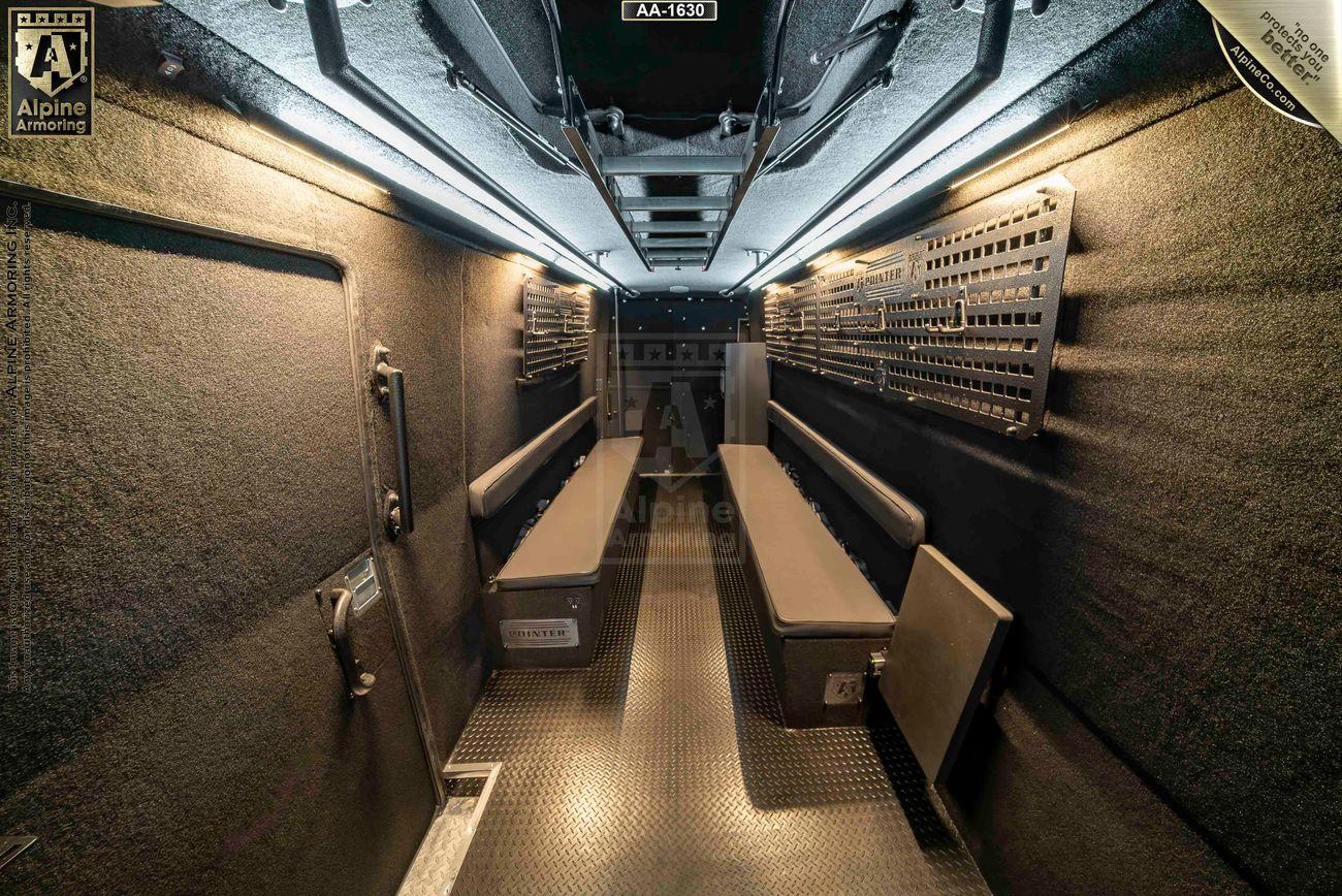 Interior view of an armored Pointer based on Mercedes Sprinter 3500XD van, showing seating benches, overhead storage, and heavily padded walls for protection.