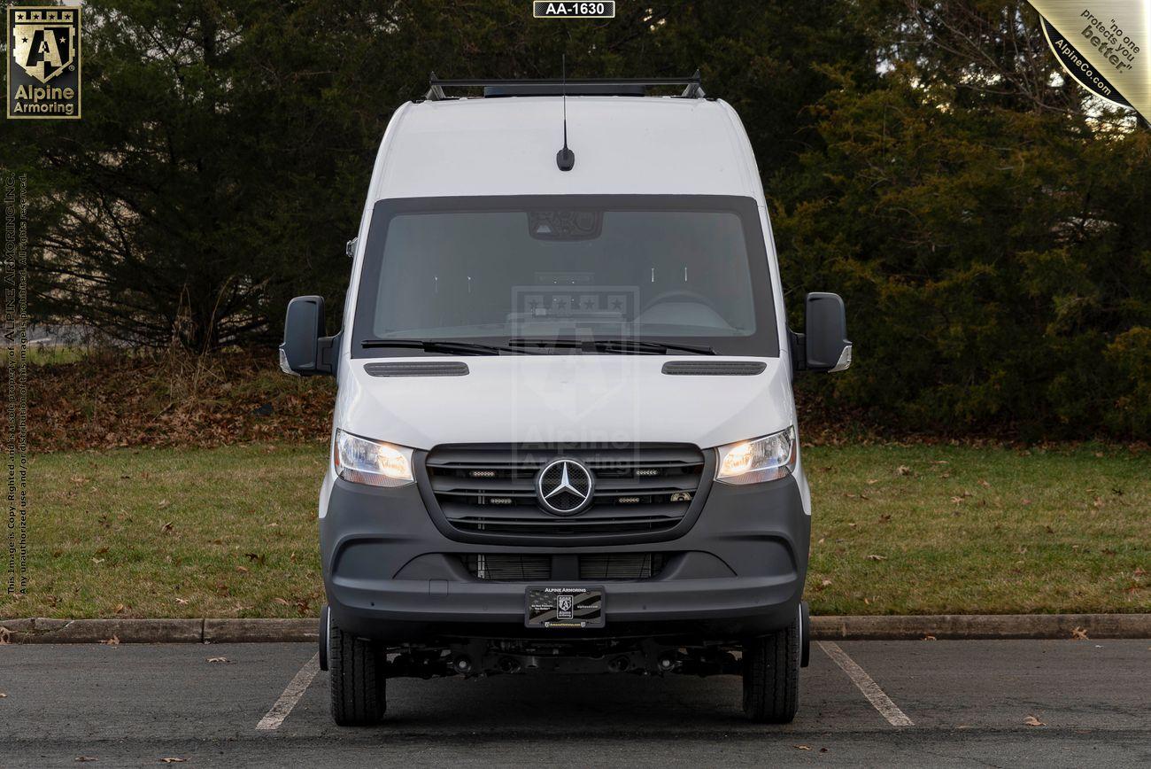 Front view of a parked white SWAT Van - Pointer®  with a Mercedes-Benz logo in an outdoor setting with trees in the background.