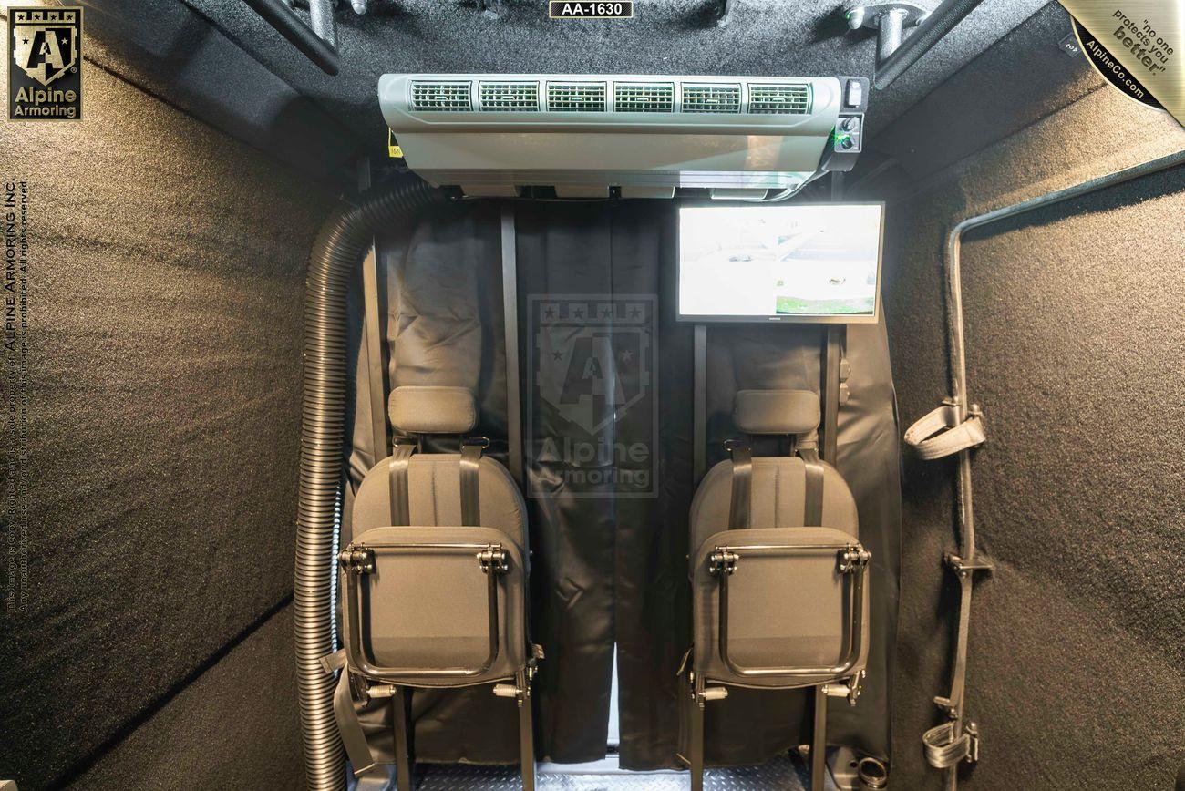 Interior of a soundproof, armored Pointer van with two facing seats, ventilation system, and an overhead screen displaying technical information.