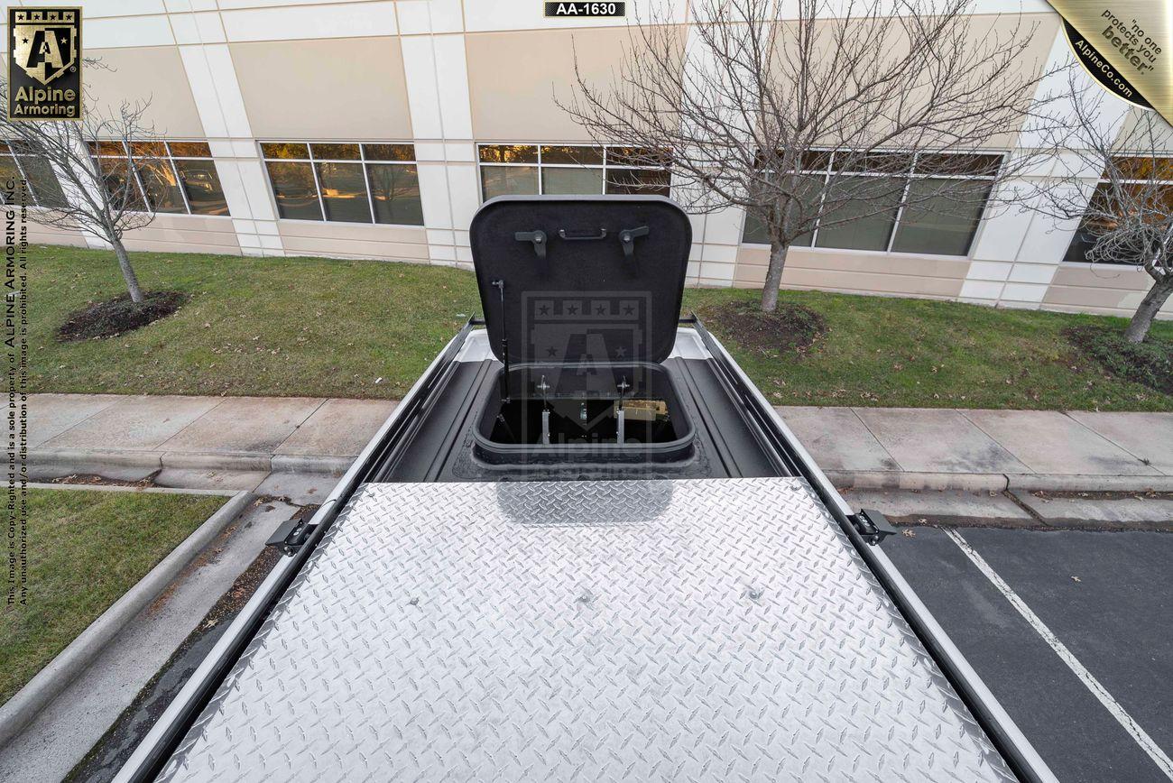 Rooftop view of a Pointer Van with an open hatch revealing a ladder inside, parked near a building with bare trees and a grassy area.