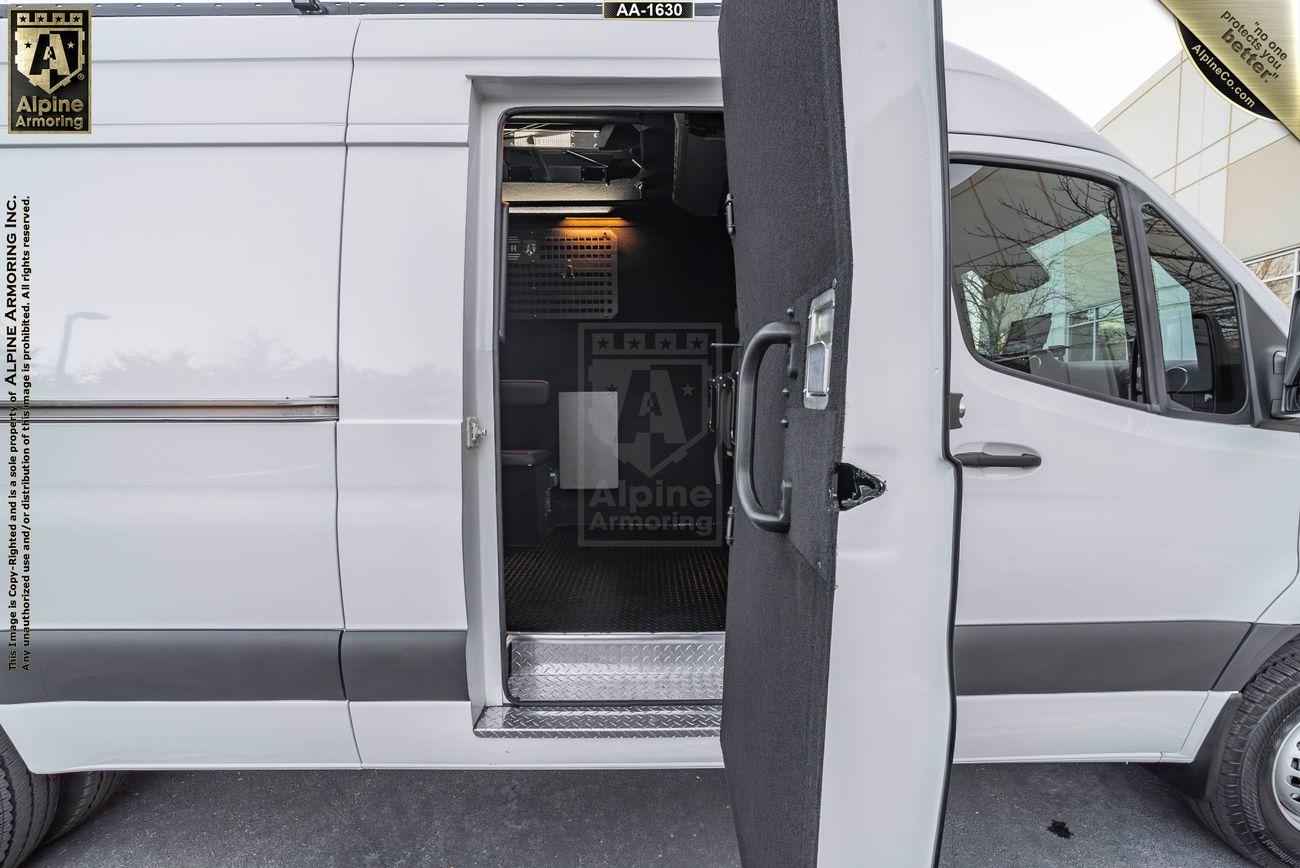 A white armored SWAT Van - Pointer is shown with its side door open, revealing the interior. The logos for Alpine Armoring are visible on the vehicle.