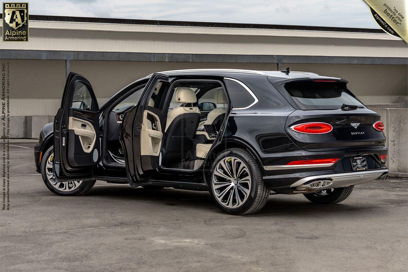 A black luxury Bentley Bentayga SUV with its doors open, showcasing the beige leather interior on a rooftop parking lot. The vehicle has a sleek design and large alloy wheels.