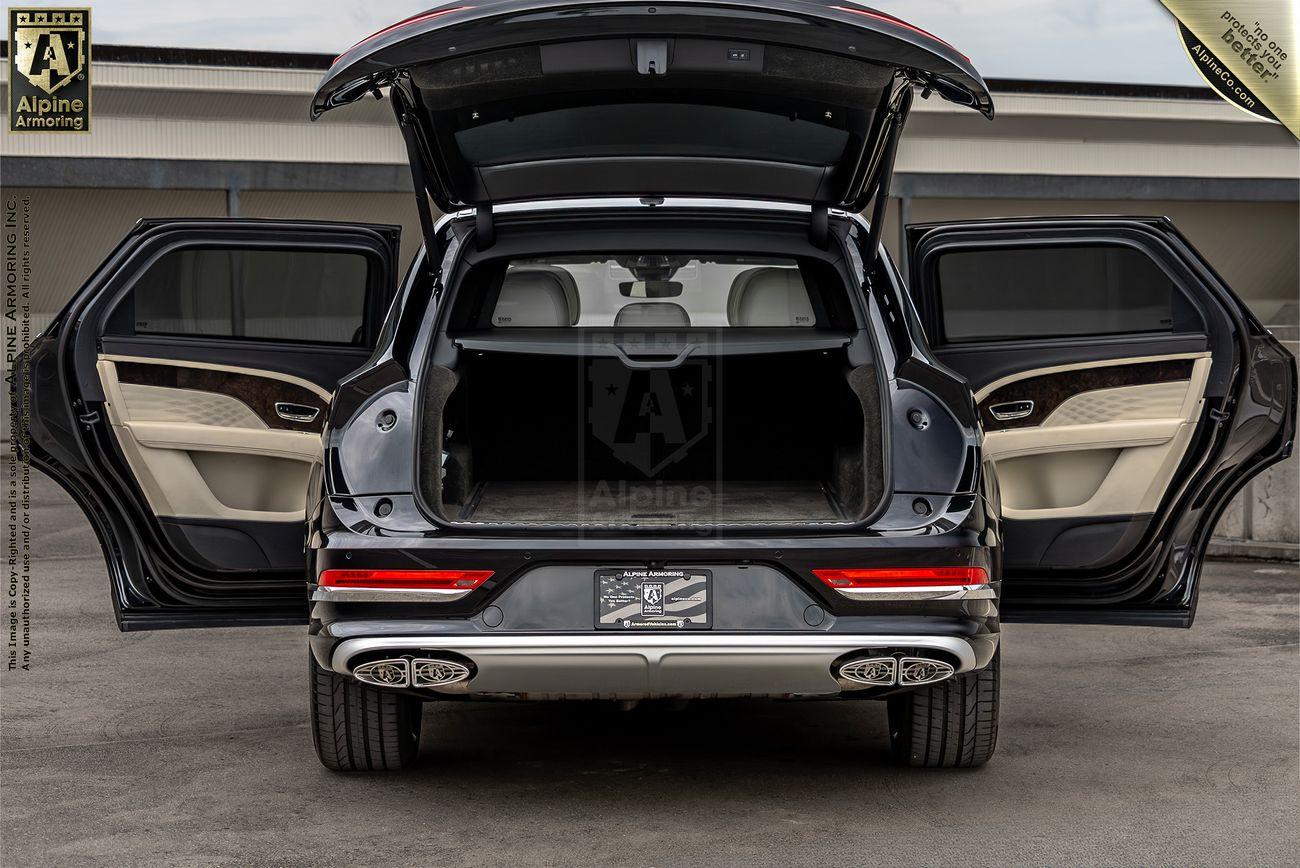 A black bulletproof Bentley Bentayga SUV with all doors and the rear hatch open, showing a beige interior, parked in a lot.