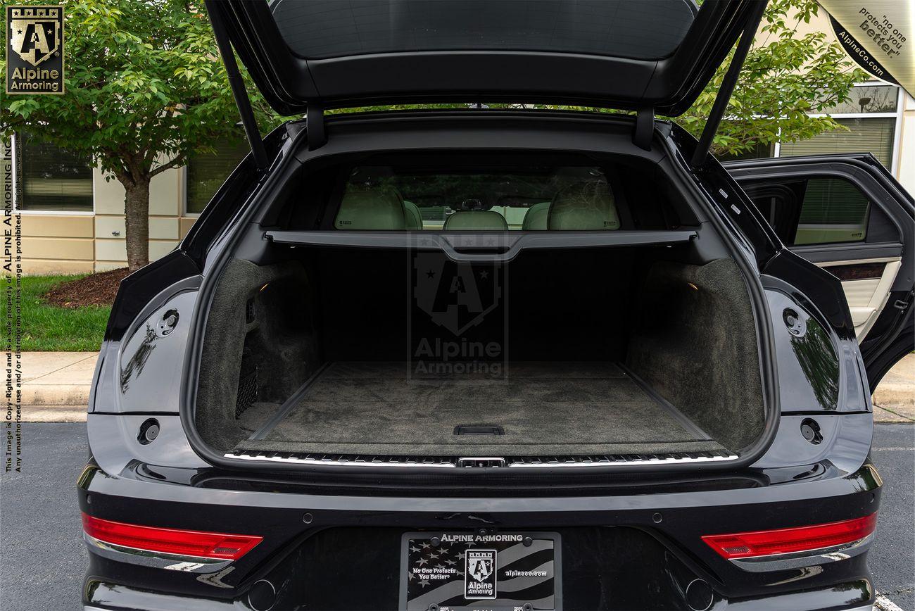 Open rear trunk of a black bulletproof Bentley Bentayga SUV with no visible cargo inside. "Alpine Armoring" branding appears on the vehicle.