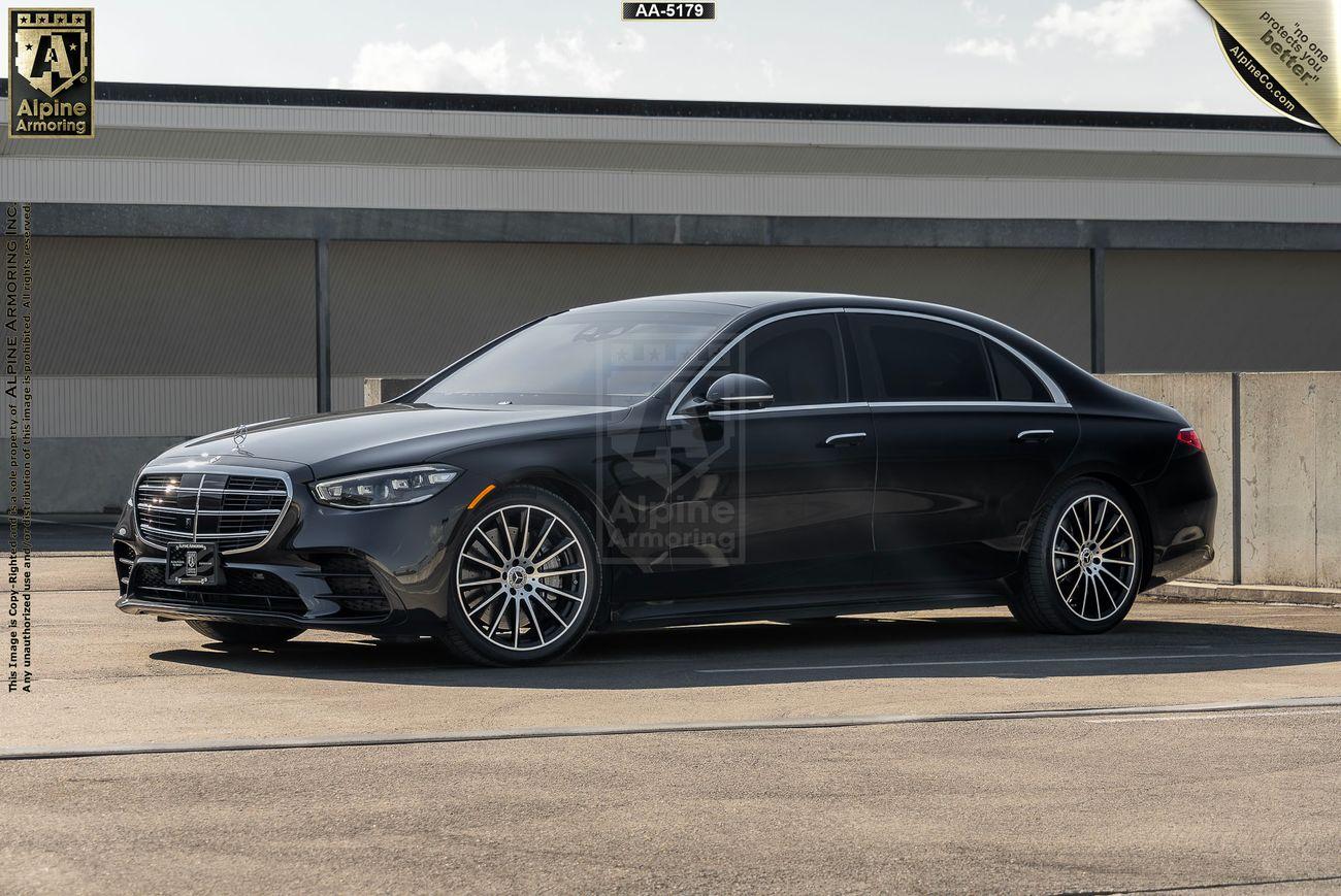 A black Mercedes-Benz S580 4MATIC from Alpine Armoring, parked outdoors. The vehicle showcases its elegant design and advanced armored features, highlighting its front and side profile in a well-lit setting.