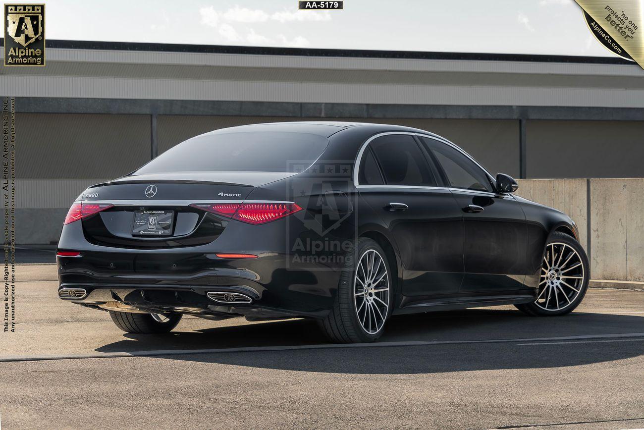 Right side view of a black Mercedes-Benz S580 4MATIC from Alpine Armoring, parked outdoors. The vehicle features a sleek design and advanced armored modifications, with a view showcasing its rear and side profile.