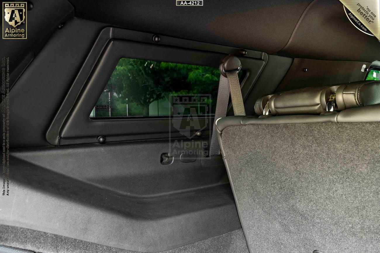 Interior view of an armored Cadillac Escalade ESV showing the back seat, a window, and a seatbelt.