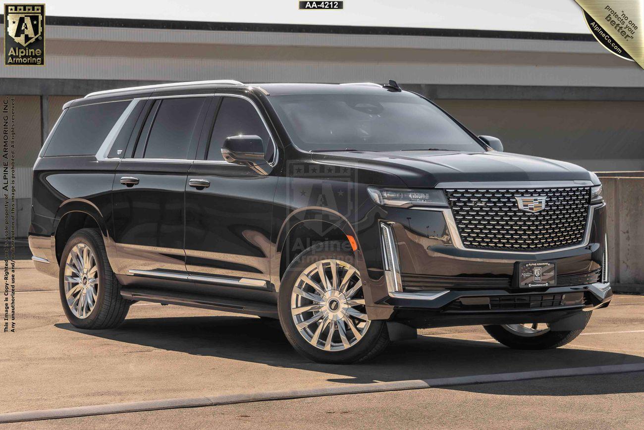 A black armored Cadillac Escalade ESV SUV is parked in an outdoor setting with a building in the background.