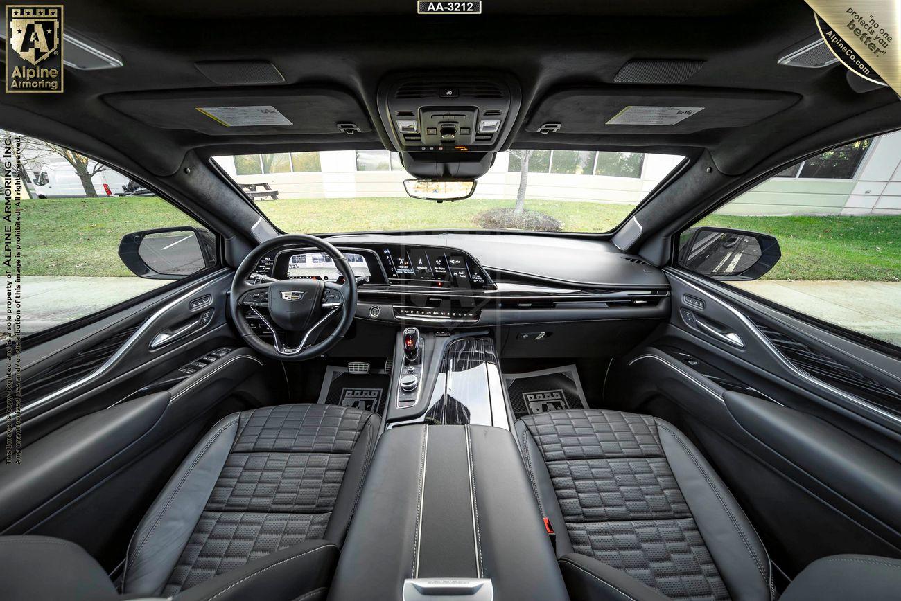 Interior view of an armored Cadillac Escalade ESV SUV  featuring a sleek, modern dashboard, a multi-functional steering wheel, and quilted leather seats.