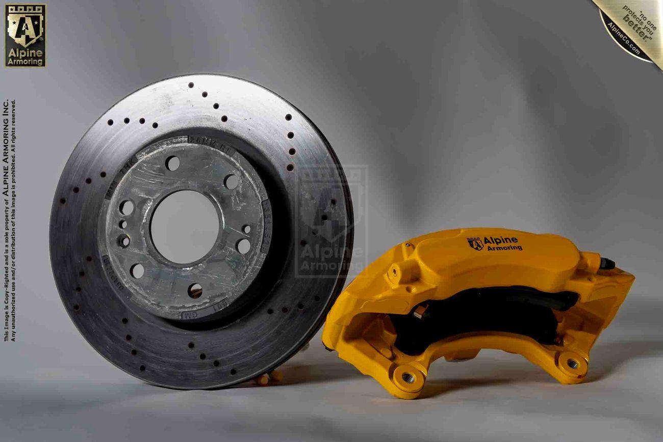 A brake rotor and a yellow brake caliper from Alpine Armoring, showcasing advanced vehicle dynamics and robust engineering for armored vehicles.