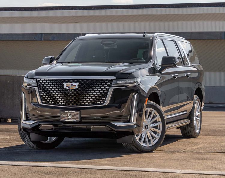 An armored black Cadillac Escalade ESV Luxury SUV is parked in an outdoor lot, viewed from the front at a slight angle. The vehicle has a large grille, alloy wheels, and tinted windows.