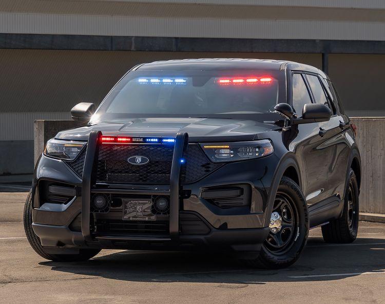 A Ford Explorer PPV SUV is parked, featuring front-facing red and blue emergency lights and a protective grille guard.