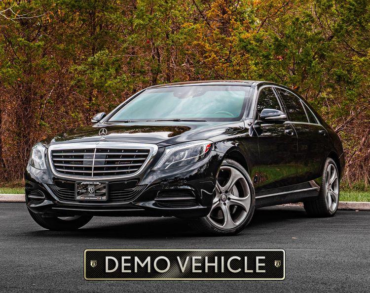 A black armored  Mercedes S550 luxury sedan parked in front of autumn trees with a sign below reading "DEMO VEHICLE.