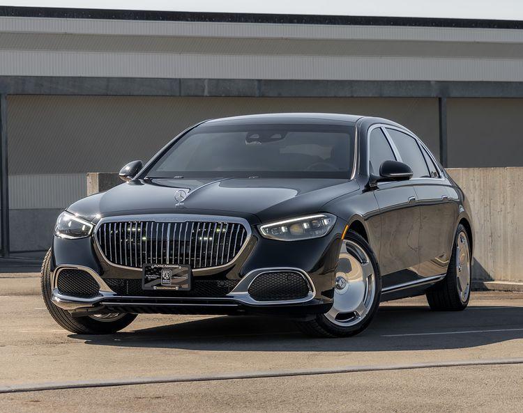 A black armored luxury sedan, specifically a Mercedes-Maybach from Alpine Armoring, parked outdoors. The vehicle features a sleek design with a prominent grille and advanced security enhancements, showcasing its blend of elegance and protection.