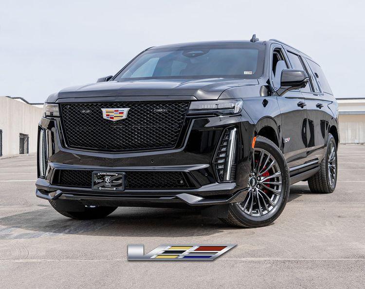 A black armored Cadillac Escalade ESV SUV is parked, featuring the Cadillac emblem on the grill and additional branding near the vehicle.