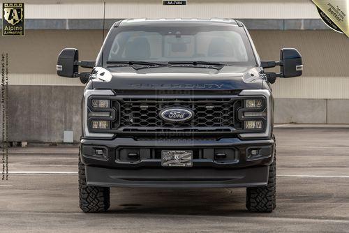 Front view of a black Ford F-Series Lariat truck parked in an outdoor lot. The truck features large side mirrors, a prominent grille, and is positioned against a concrete background with overhang.