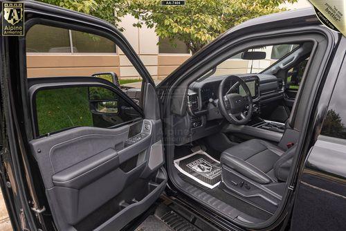 The front interior of a black armored Ford Super Duty F-350 Lariattruck with both the driver and passenger doors open, revealing a modern, clean dashboard and spacious seating area.