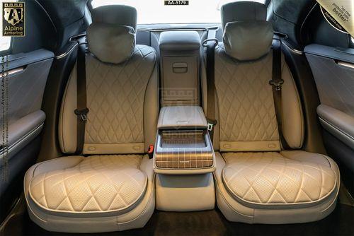 Rear interior of a Mercedes-Benz S580 S-Class 4MATIC featuring two quilted leather seats, a center armrest with controls, and wood trim details.