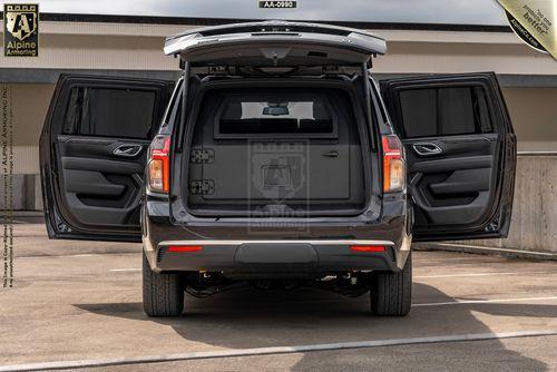 A black bulletproof Chevrolet Suburban LT  SUV with its rear doors open, showing the interior of the cargo area.