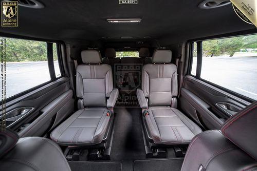 Interior of a luxury, armoured Chevrolet Suburban RST SUV featuring four leather bucket seats and large windows.