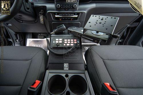 Interior of a Ford Explorer PPV showing the front seats, a center console with cup holders, a mounted tablet holder, and a control panel with buttons and a microphone, likely for communication purposes.