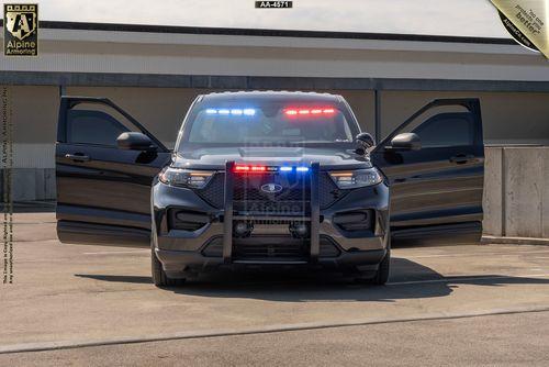 A black police Ford Explorer PPV with its blue and red emergency lights turned on, positioned in front of a building with both front doors open.