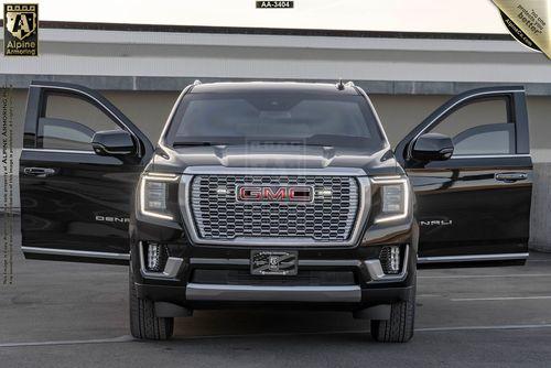 Front view of a black armored GMC Yukon Denali XL with the front doors open to show windows rolled down partially.