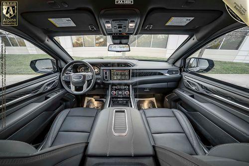 Interior of a GMC Yukon Denali XL featuring a black leather interior, a multifunction steering wheel, a digital dashboard, and a center console with multiple controls and compartments.