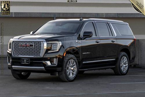 Front, left view of a black GMC Yukon Denali SUV is parked on a concrete surface in an outdoor setting.