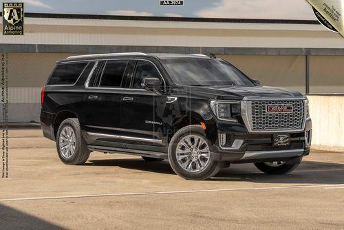 A black GMC Yukon Denali SUV XL is parked in an outdoor setting on a concrete surface. The vehicle is shown from a front-side angle with clear details of its grille, wheels, and windows.