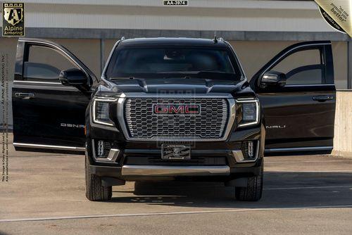 A black GMC Yukon Denali XL SUV is parked with both front doors open. The vehicle is viewed from the front, showcasing its grill and headlights. The interior and side mirrors are partially visible.