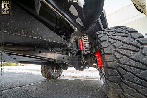 Low-angle view of a lifted Mastiff suspension and shock absorber system with large off-road tires on a clean driveway.