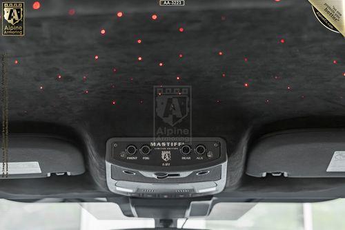 Close-up of a Mastiff's interior roof, featuring a black panel with small red LED lights and a control console labeled "Alpine" and "Mastiff" with buttons for front, rear, and auxiliary functions.