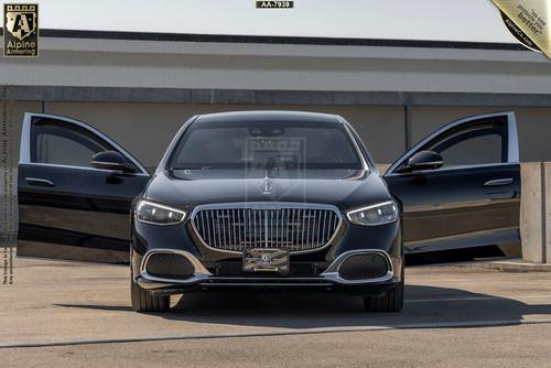 Front view of a black Mercedes-Benz Maybach with both front doors open, parked on a concrete surface.