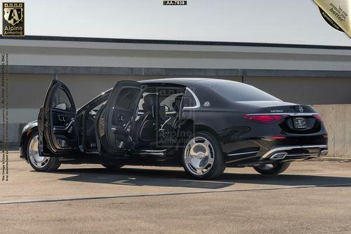 An armored Meredes Maybach viewed from the rear in a parking area. The sedan has both driver side doors open.