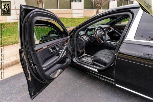 Open front driver's side door of a black Mercedes-Benz Maybach, showing a clean interior with quilted leather seating and a sleek dashboard.