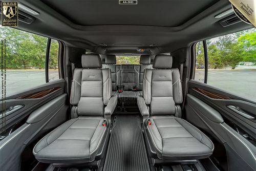 Interior view of an armored Cadillac Escalade ESV Premium Luxury SUV showcasing two rows of gray leather seats with ample legroom and sleek design elements.