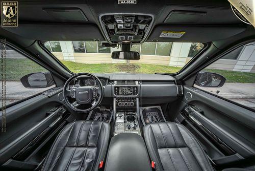 Interior view of a Range Rover Autobiography showcasing the front seats, dashboard, steering wheel, and central console with various controls and displays.