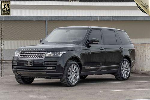 A black Range Rover Autobiography SUV is parked in an outdoor lot with a concrete wall and metal railing in the background. The vehicle's front and side are visible.