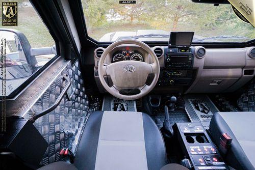 The inside of a SWAT APC CUDA looking at the dash from behind the driver's seat.  The Alpine Armoring logo is in the upper left corner.